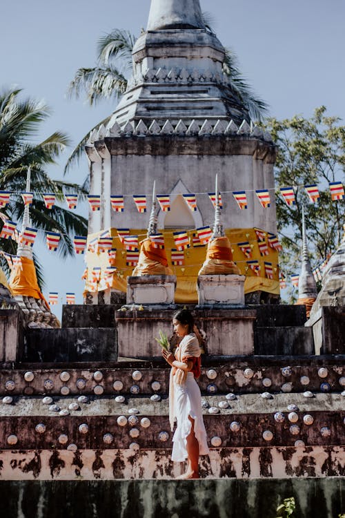 Woman in a White Dress Standing in Front of Buddha Temple