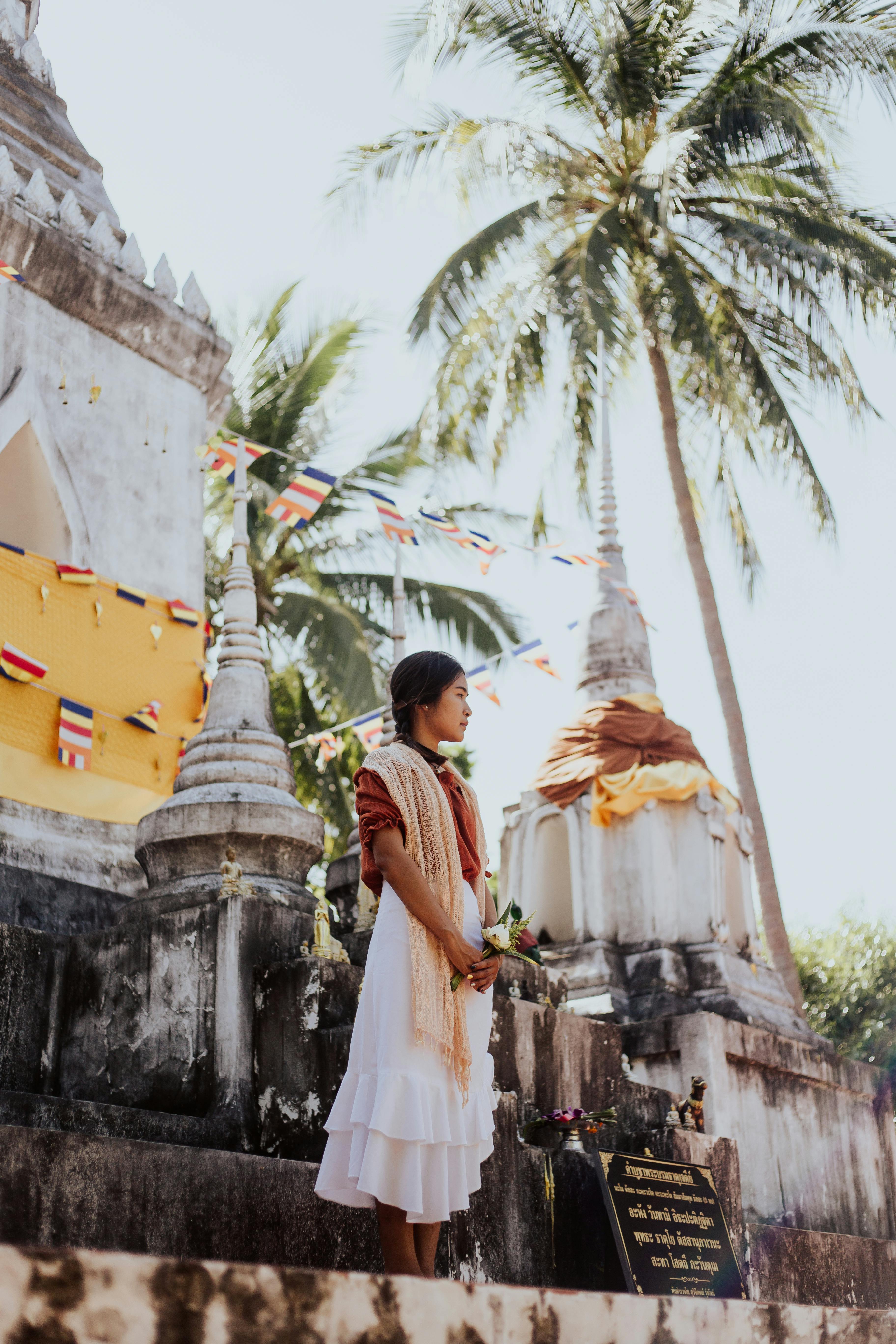 woman in traditional clothing standing by wat thai sarnath temple