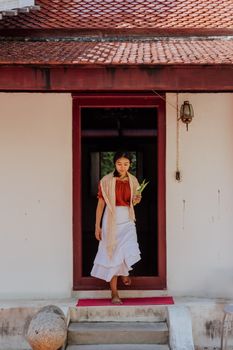 一名穿着传统服装的亚洲妇女从一栋入口有楼梯的老式建筑里走了出来