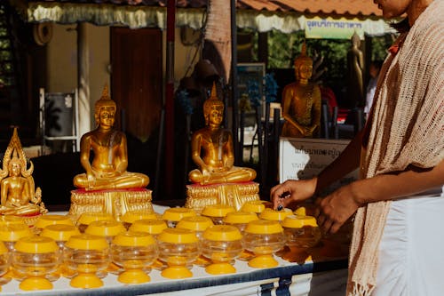 Person Standing by Stand with Buddha Figurines and Items