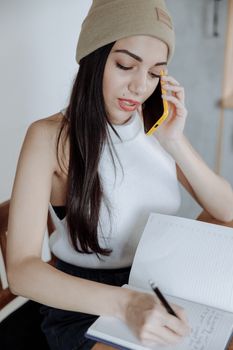 专注的年轻女性一边打电话一边做笔记，体现了生产力和多任务处理能力