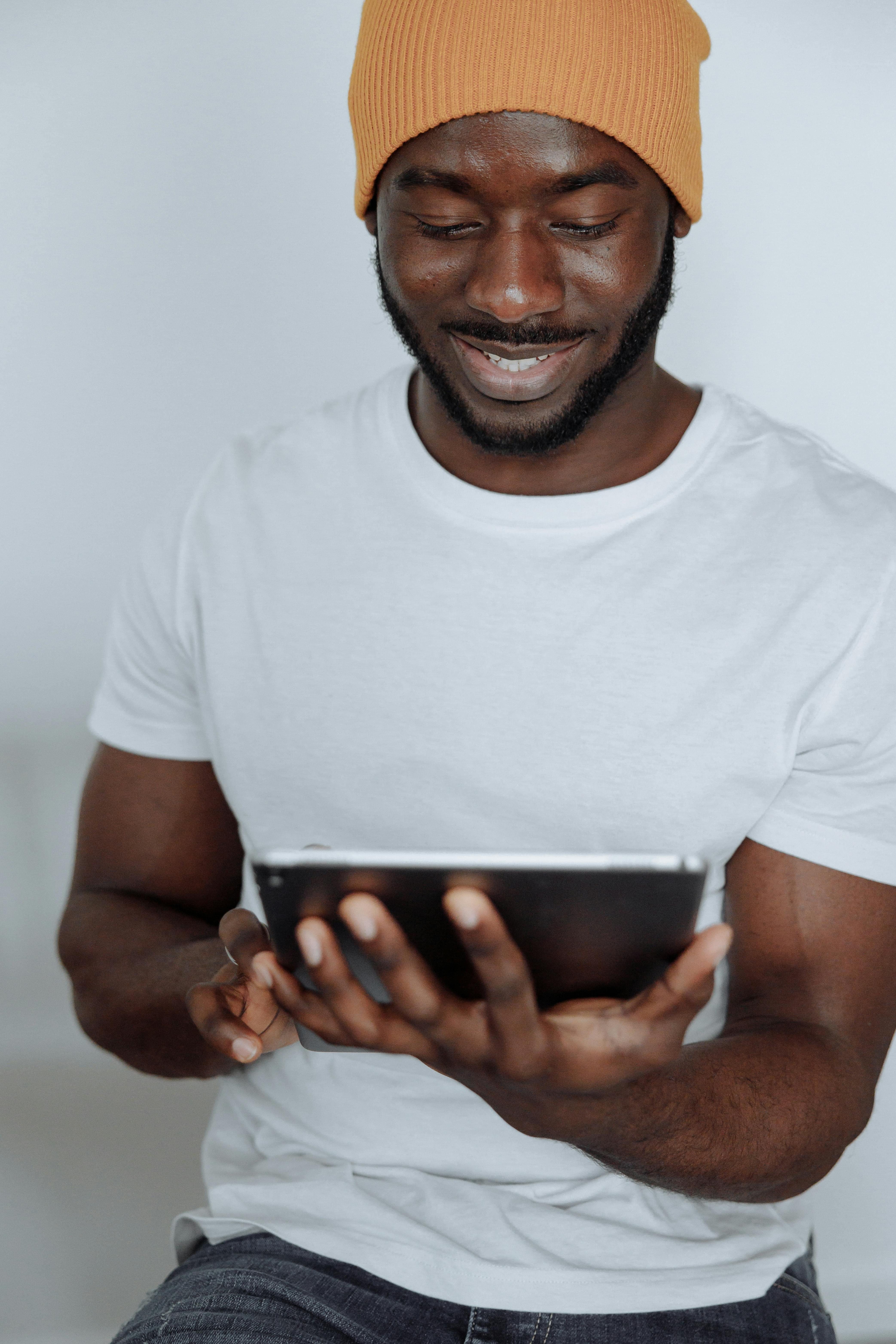 man in white crew neck t shirt holding black smartphone