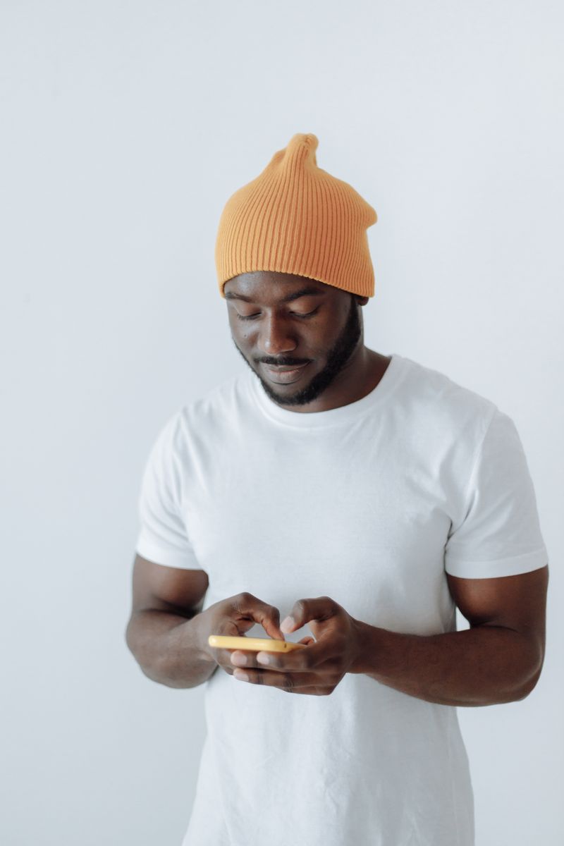 Person in an amber beanie checking a phone — photo by Thirdman on Pexels