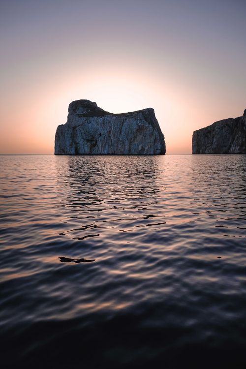 Free Spectacular scenery of rough rocky formations in rippling sea water against cloudless sundown sky Stock Photo
