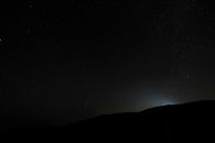 从下方望去，山脉的轮廓映衬着黑暗的夜空，山谷中星光闪烁