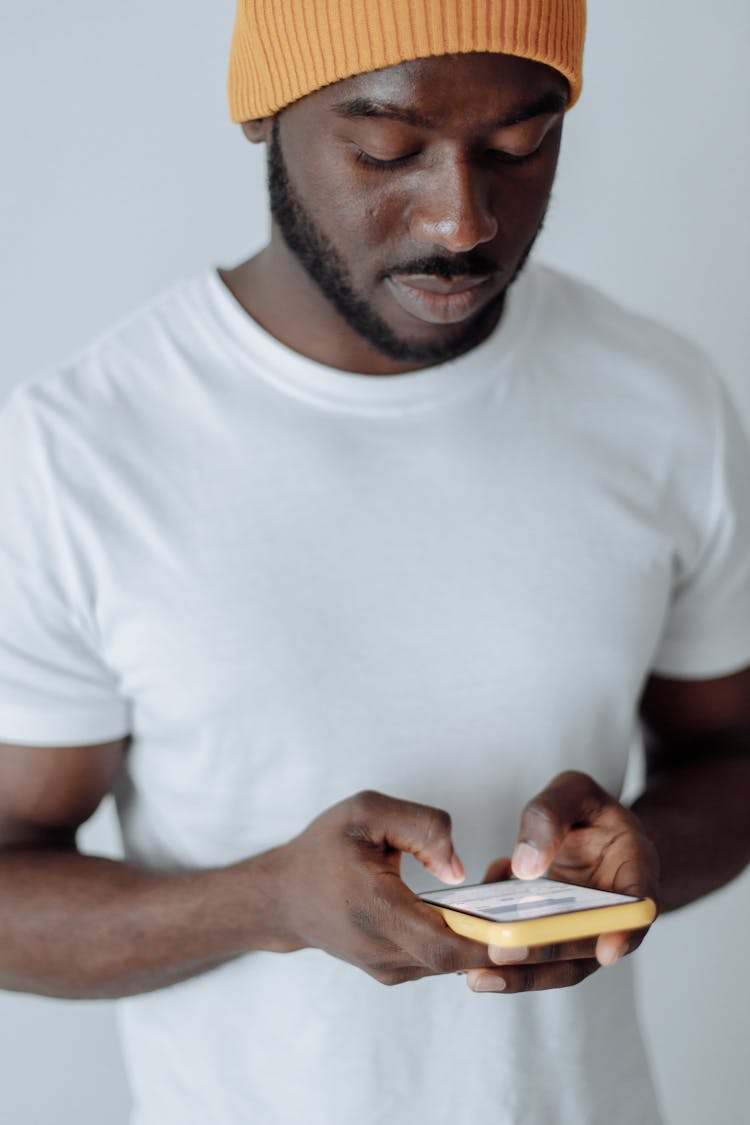 A Man In A White T Shirt Using A Cellphone