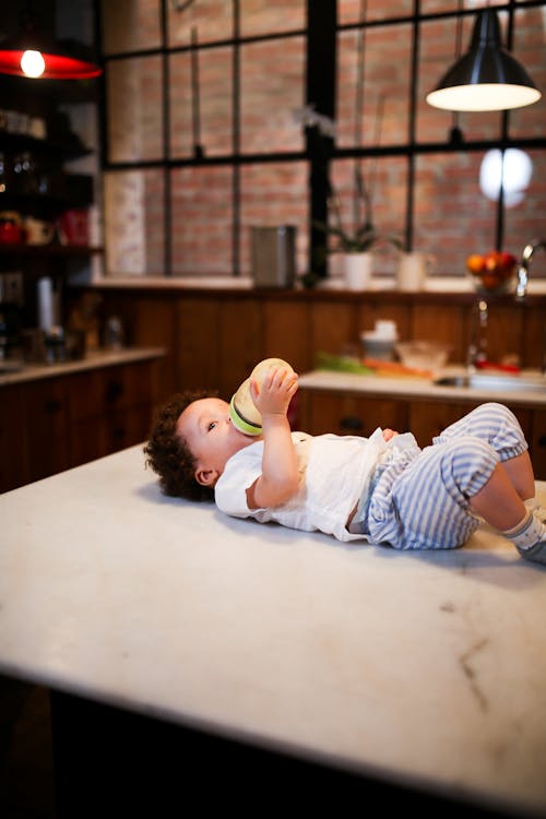 Free A Child Drinking Milk While Lying Down on a Kitchen Counter Stock Photo