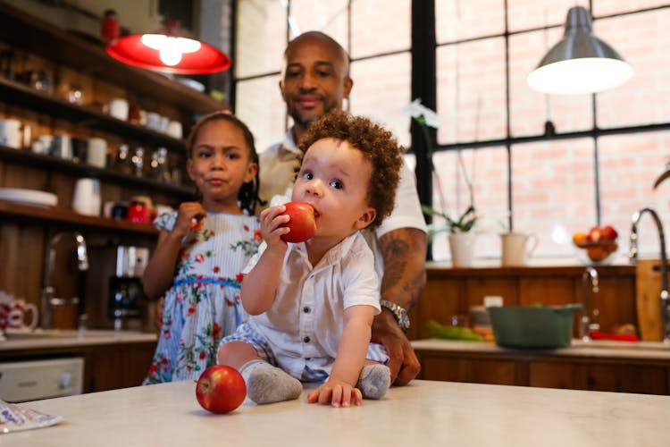 A Little Boy Eating An Apple On A Kitchen Counter Top