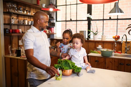 A Man Making a Salad with his Kids in a Kitchen