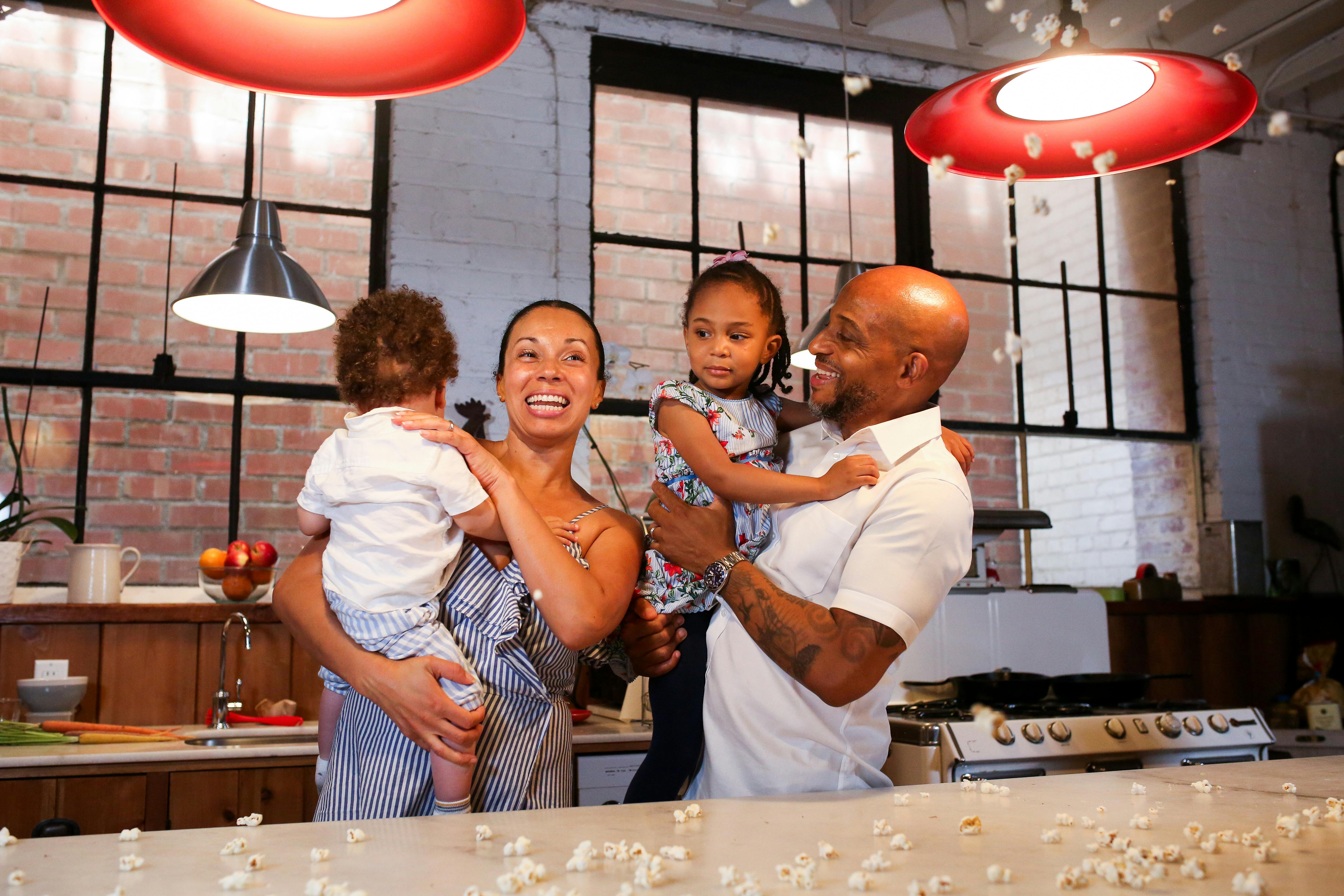 a couple carrying their children in a kitchen