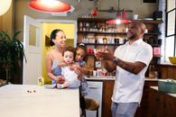 A Man Juggling Apples in Front of his Family in a Kitchen