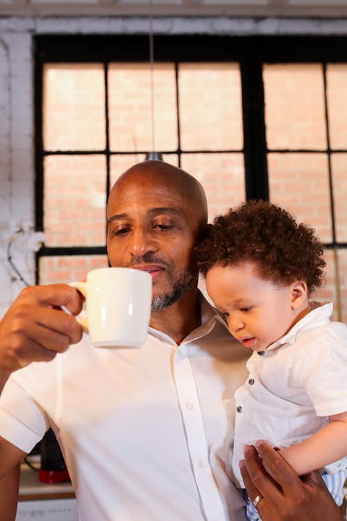 A Man Having Coffee while Carrying his Son