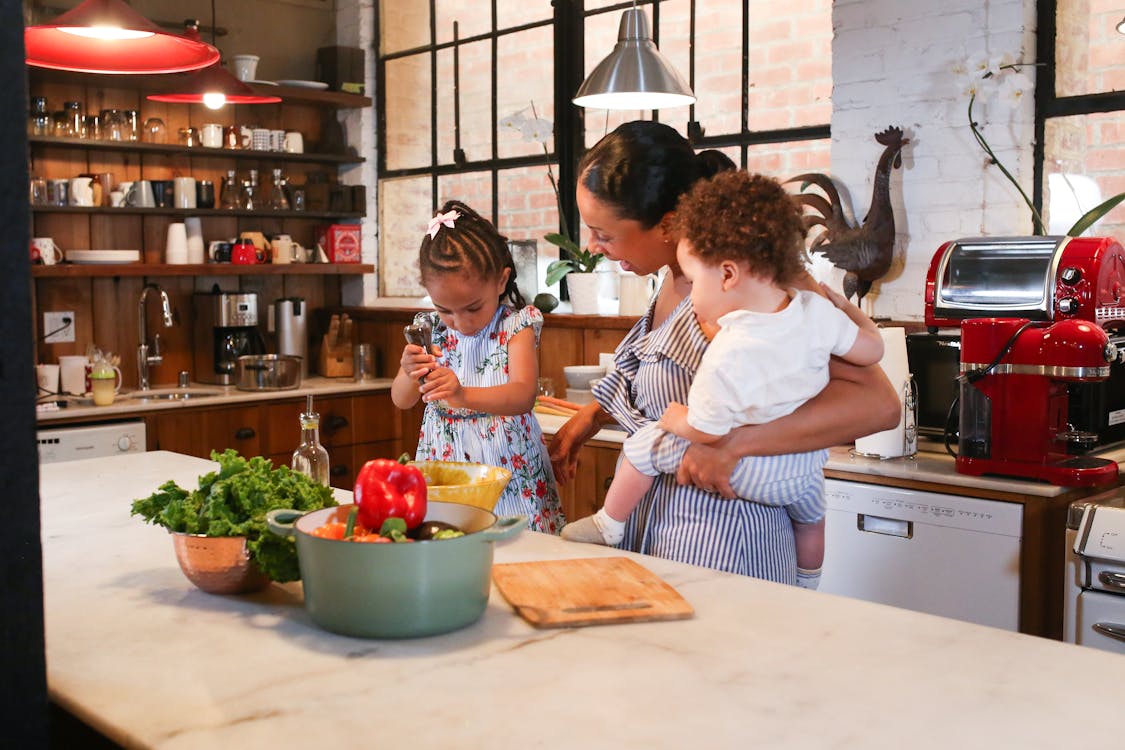 Free A Little Girl Preparing Food with her Mother in a Kitchen Stock Photo