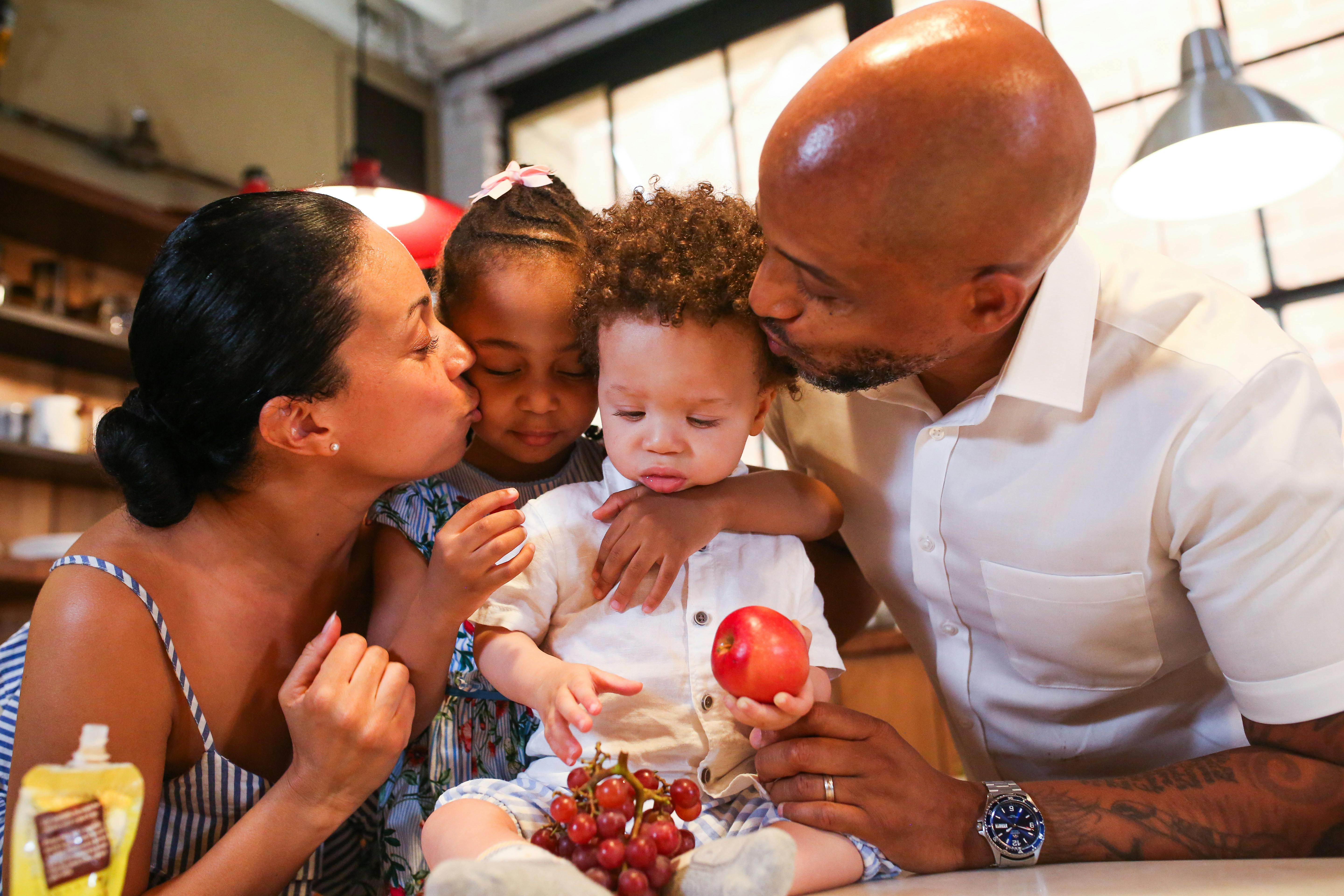 a couple kissing their children