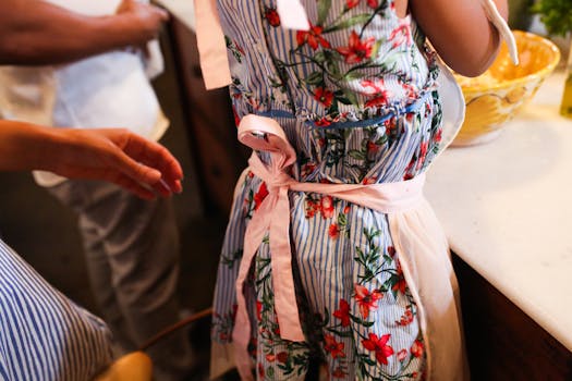 Close-up of a floral apron tied around a person in a warm kitchen scene.