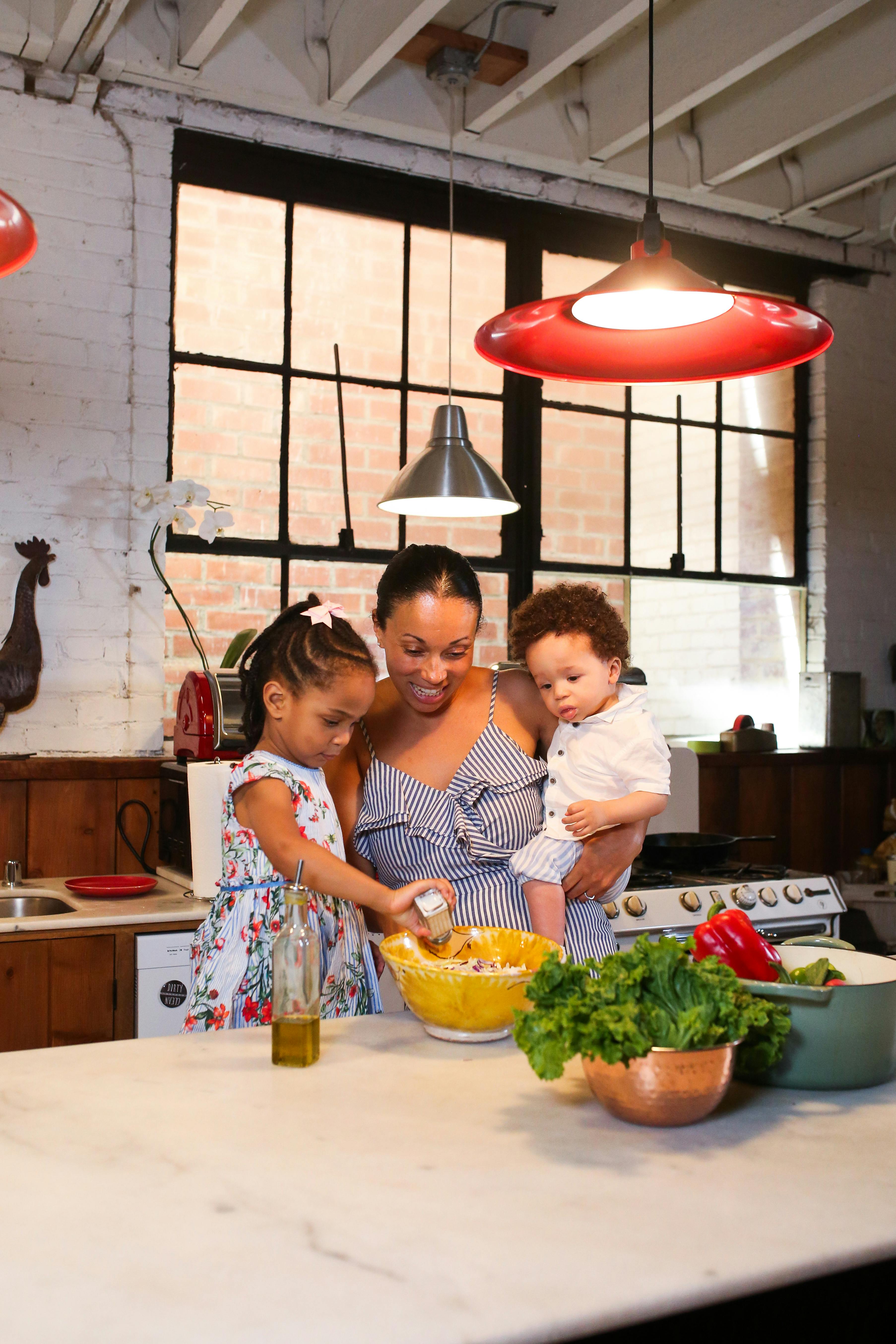 a woman and her children preparing food in a kitchen