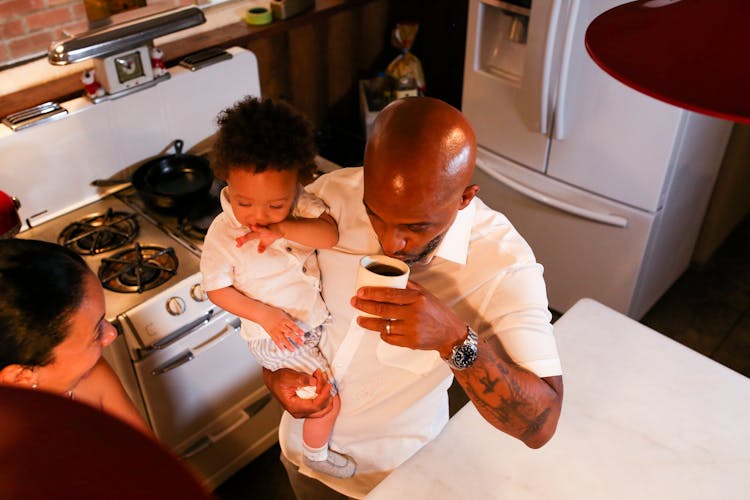 A Father Drinking Coffee While Carrying His Son