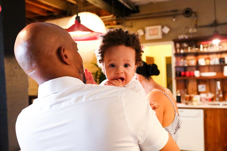 Back View Shot Of A Man In White Polo Carrying A Baby Boy