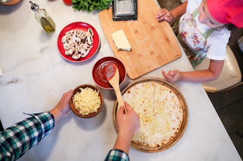 Father and Daughter Preparing Pizza on Kitchen Counter Table