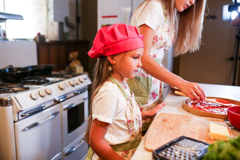Photo by RDNE Stock project on Pexels Young girl and woman in kitchen preparing food, wearing aprons and chef hats.