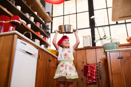 Little Girl Standing in Floral Apron and Chef Hat Holding a Casserole