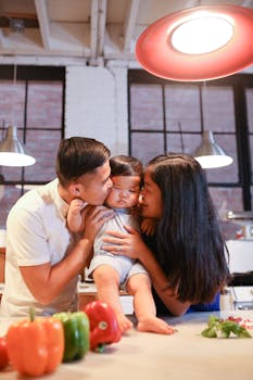 Asian parents hug their toddler in a cozy kitchen setting, showcasing warmth and love.