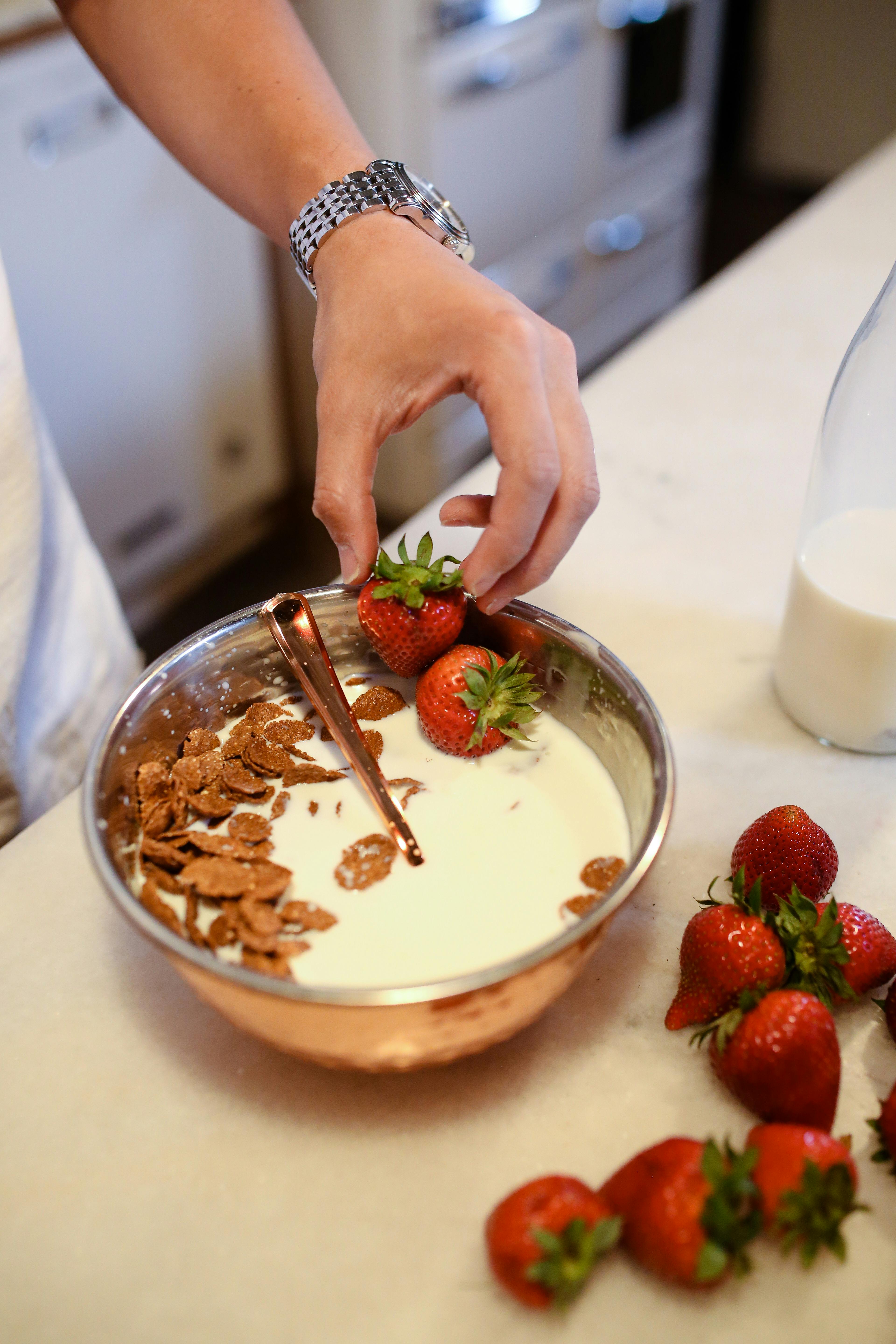 person holding stainless steel bowl with strawberries