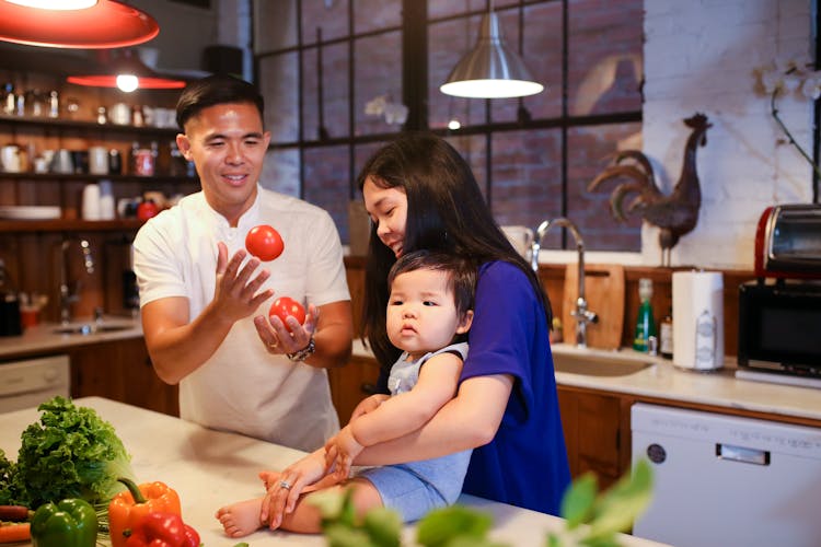 A Couple Playing With Their Baby In A Kitchen