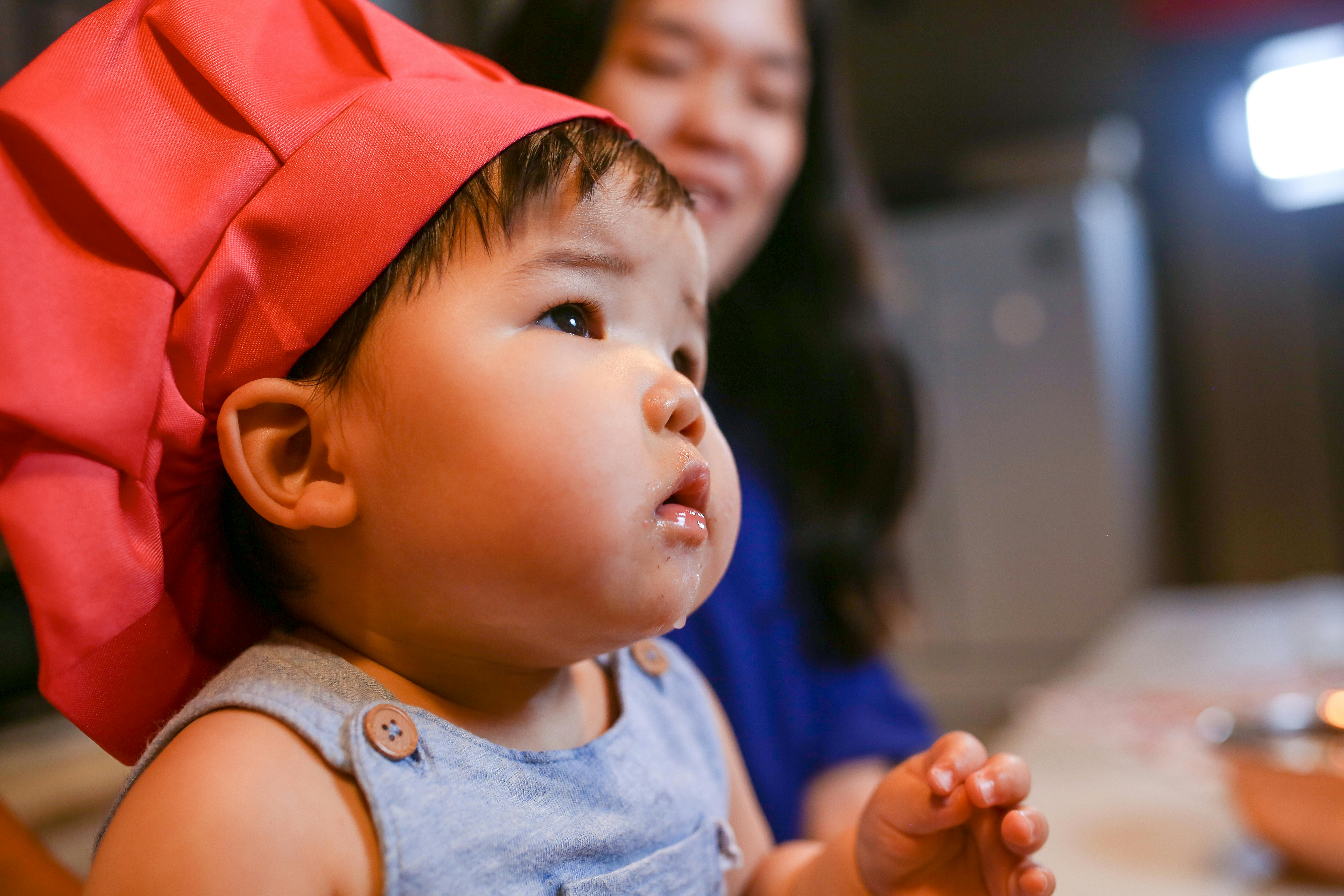 toddler wearing red chef hat looking up