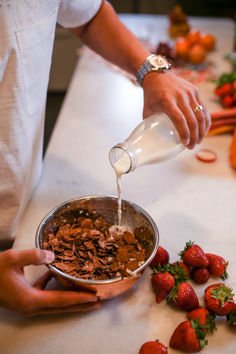 A Close-Up Shot Of A Man Pouring Milk In A Bowl Of Cereal