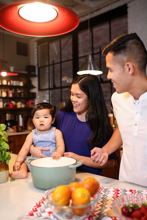 A Couple Looking at a Baby Sitting on a Kitchen Counter