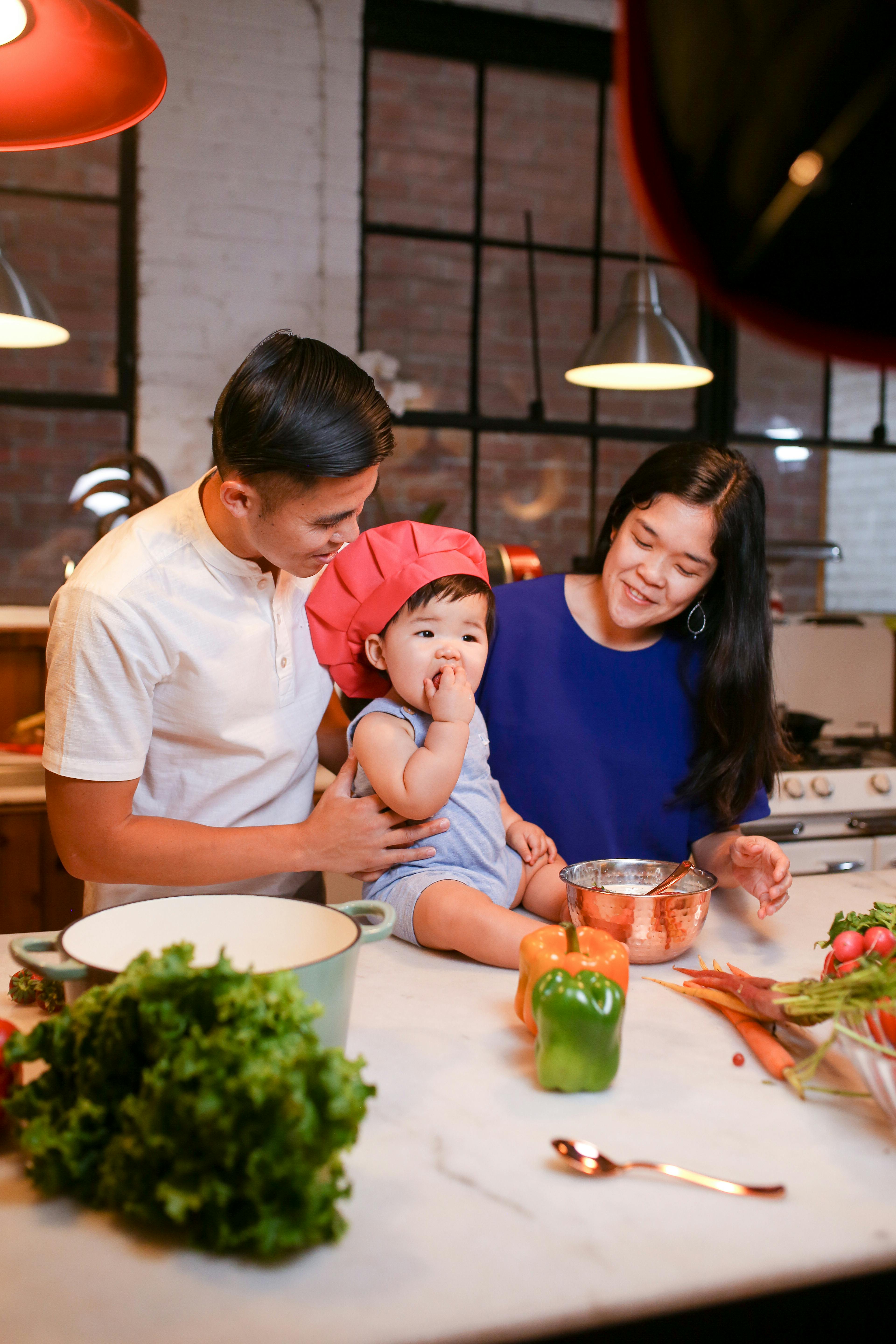 a couple looking at a baby sitting on a kitchen counter