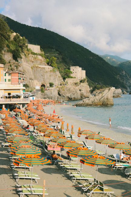 From above of colorful shoreline with chaise loungers under umbrellas located in rocky authentic settlement on cloudy summer day