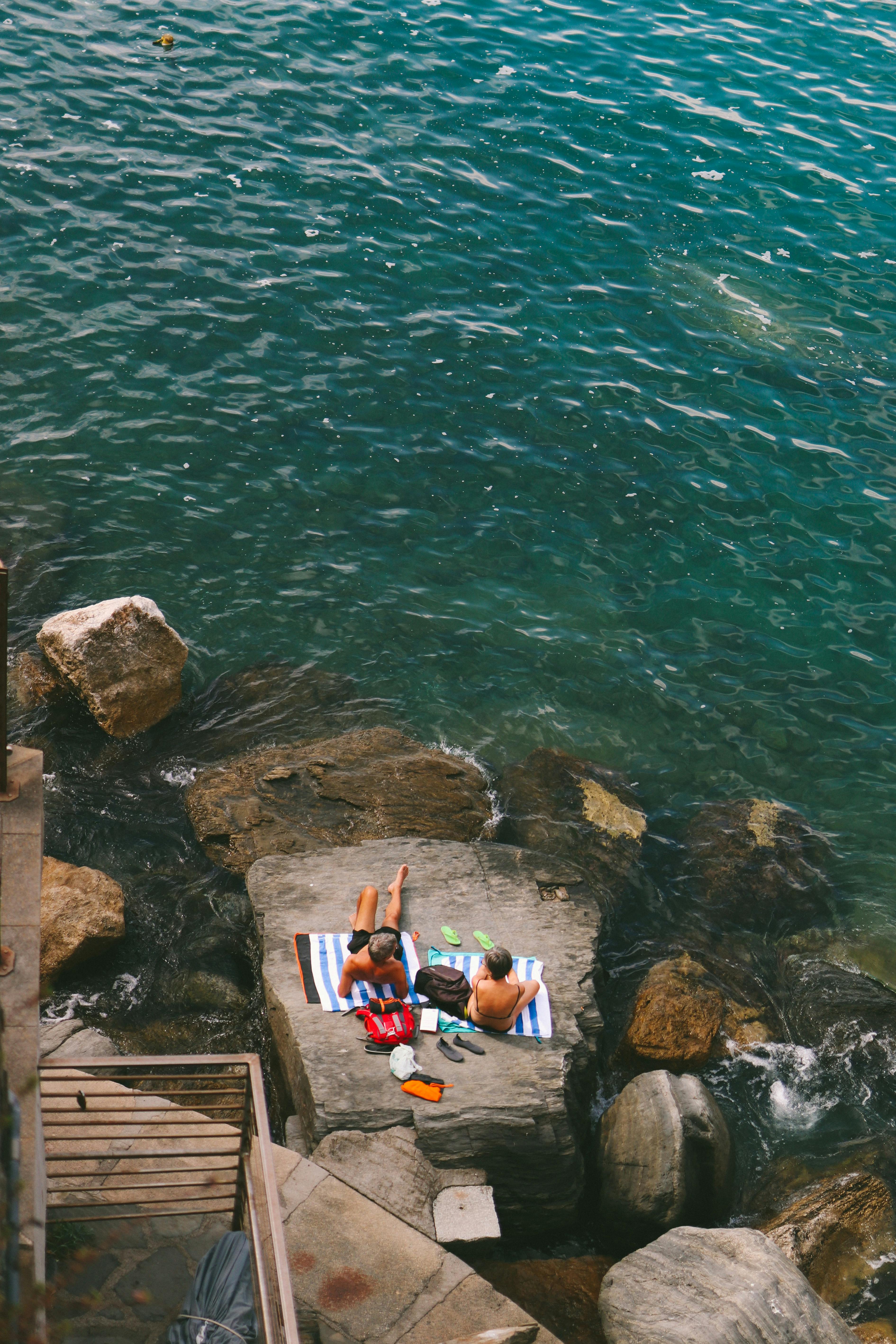 unrecognizable couple chilling on stony seashore