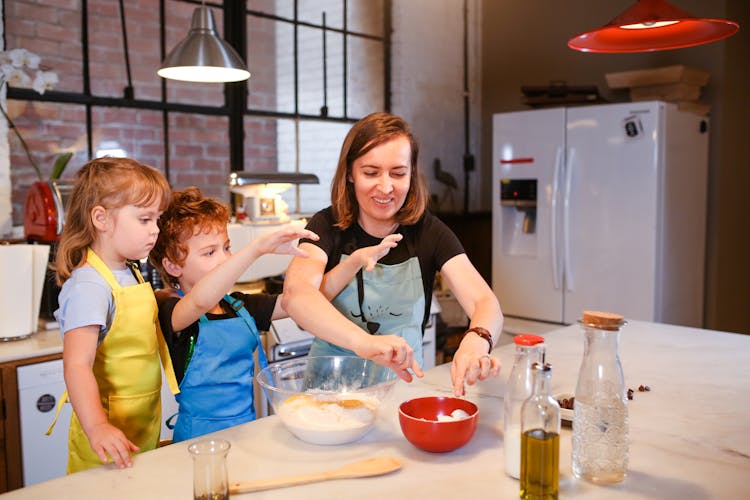 Mother Is Baking Together With Her Children In The Kitchen