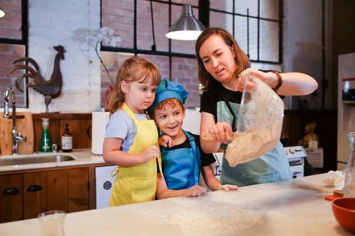 Free A mother and children baking together in a cozy kitchen, sharing quality time. Stock Photo