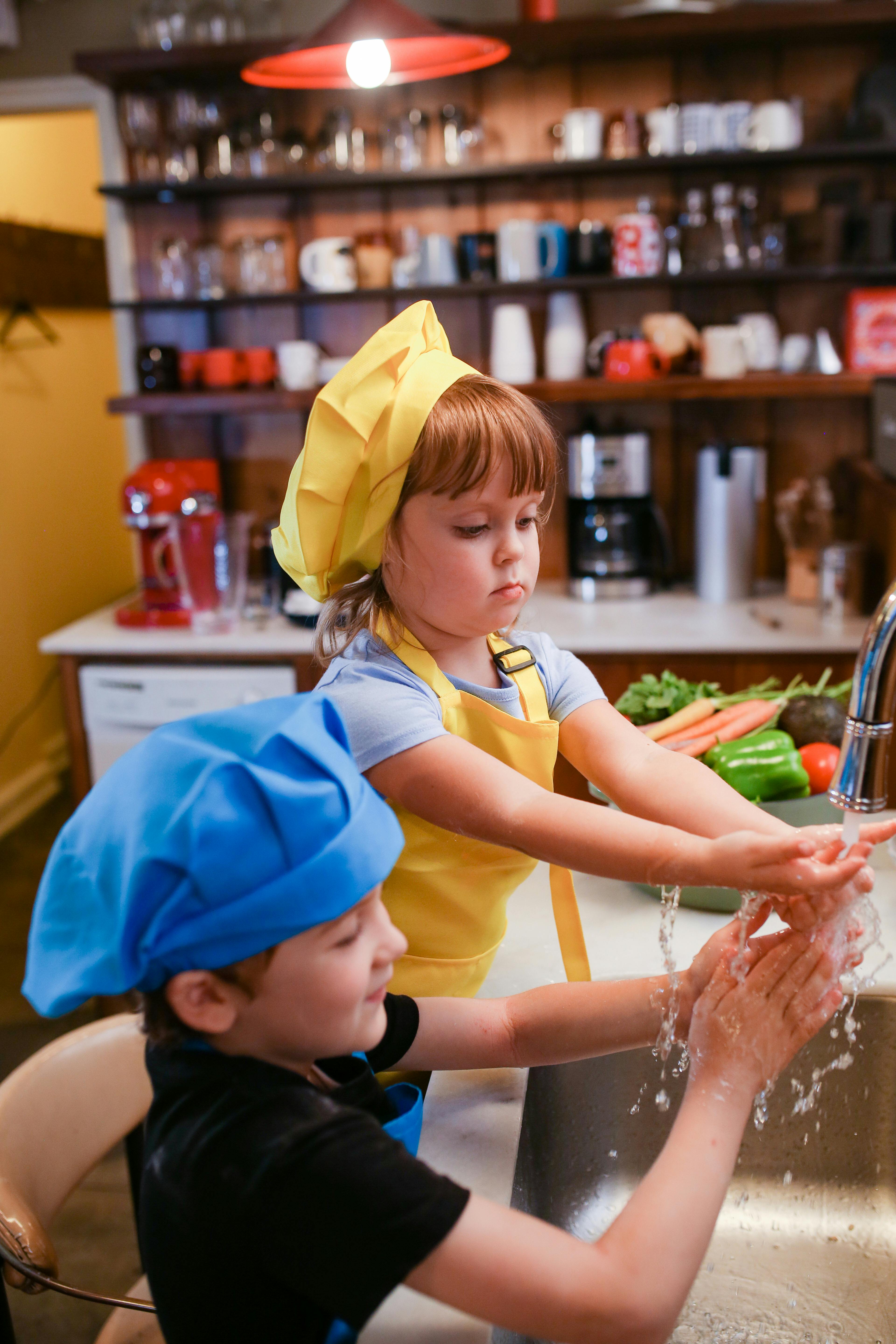 children in chef s hats washing their hands