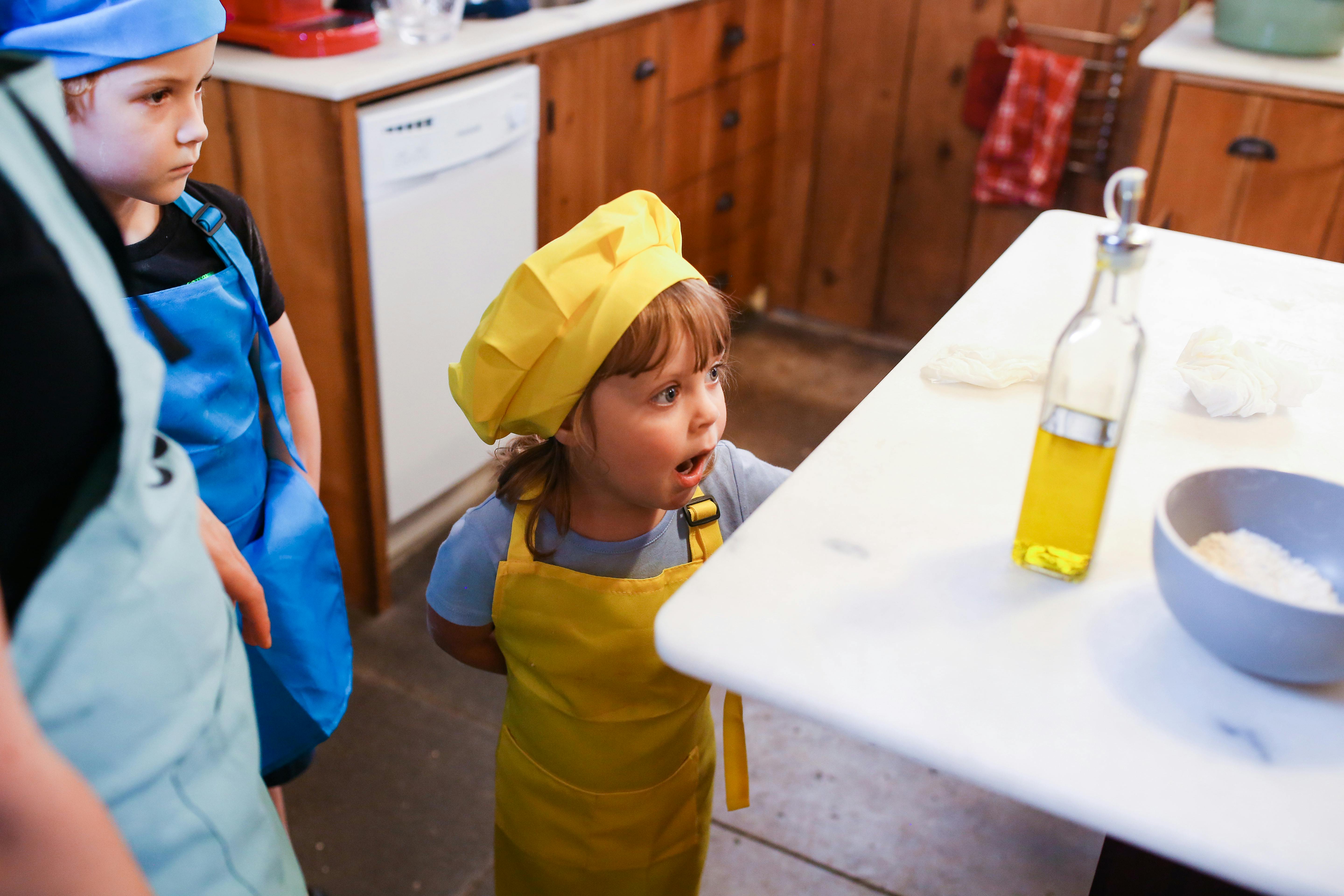 a girl in yellow apron looking at the glass bottle