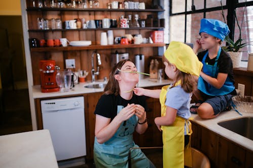 A Woman Playing with her Children in a Kitchen