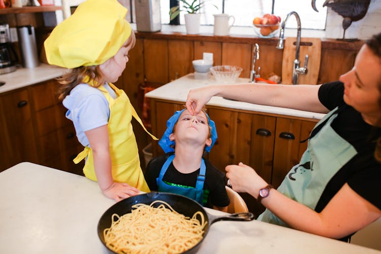 A Boy In Blue Apron Eating Pasta