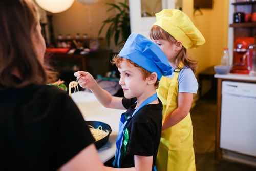 Free Children wearing chef hats cooking pasta in a lively kitchen setting. Inspiring young chefs. Stock Photo