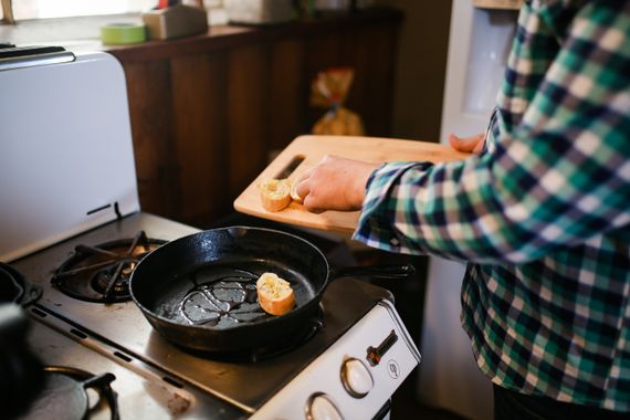 Home cook holding a frying pan while preparing food on a stove