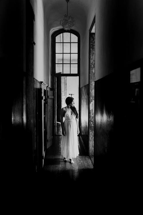 寧靜的女人站在狹窄的老建築走廊