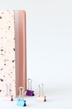 一张极简主义的图像展示了一本现代水磨石图案笔记本旁的彩色夹片