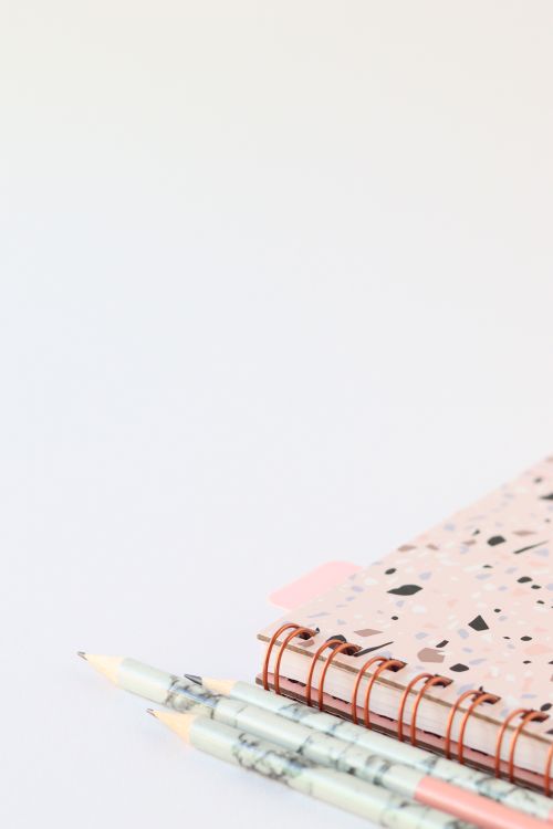 Free An artistic composition featuring a stylish notebook and two pencils on a white background with ample copy space. Stock Photo