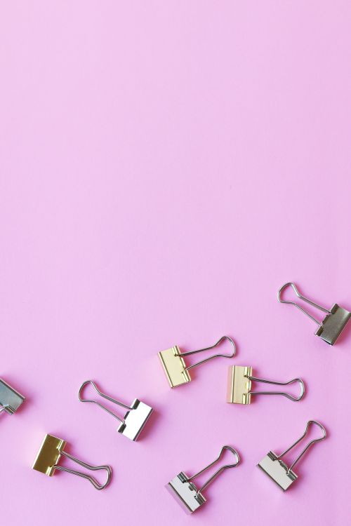 Free Overhead view of assorted binder clips on a vibrant pink surface with ample copy space. Stock Photo
