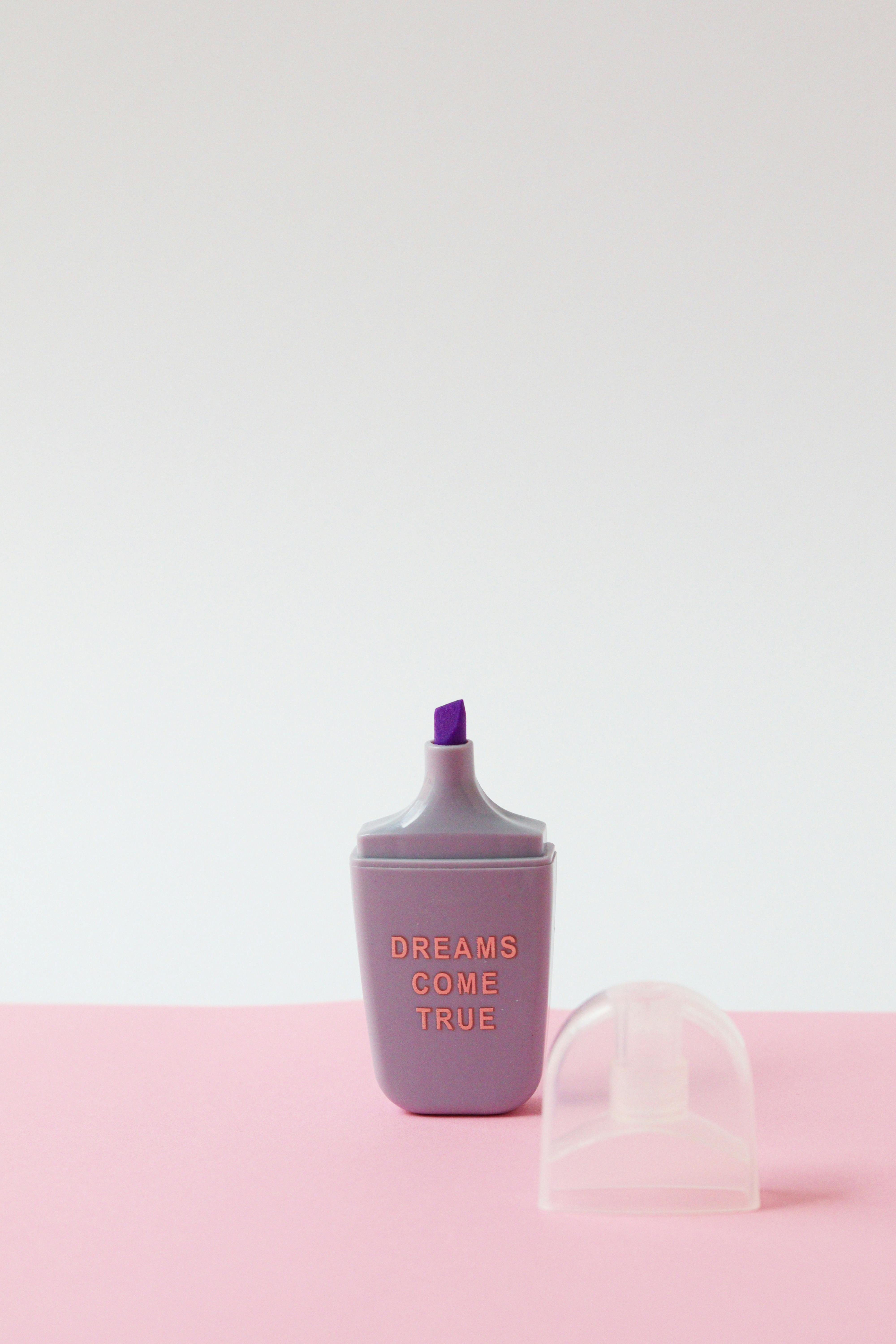 Purple highlighter with 'Dreams Come True' text on a pink background, creating an inspiring minimalist composition.