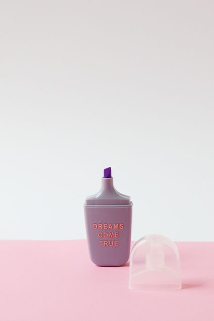 Purple highlighter with 'Dreams Come True' text on a pink background, creating an inspiring minimalist composition.