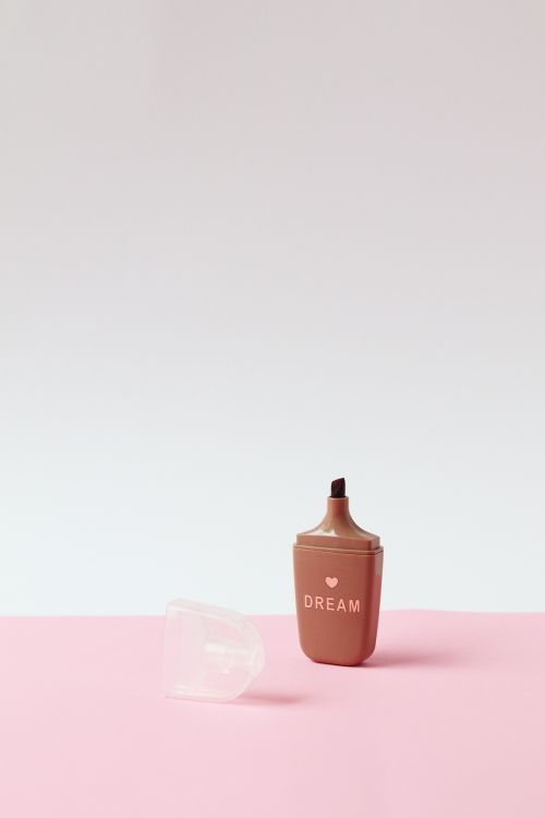 Free Minimalist photo of a brown highlighter with 'DREAM' text, on a pink background. Stock Photo