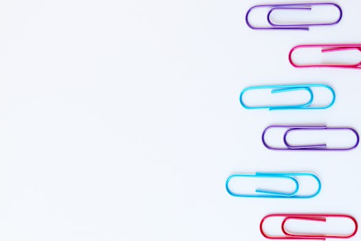 Vibrant paperclips arranged on a white background with ample copy space.